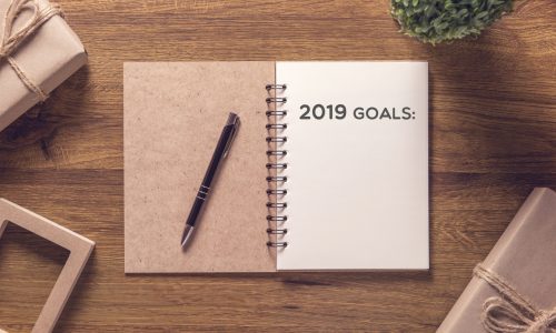 2019 goals list in notebook with gift box new year on wooden table background.