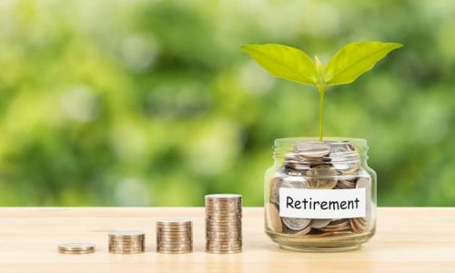 Coin glass jar container and stack on wooden desk, retirement saving concept, on green tree background