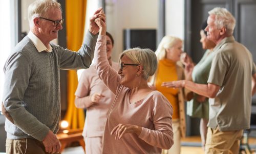 Group of smiling senior people dancing while enjoying activities in retirement home, copy space