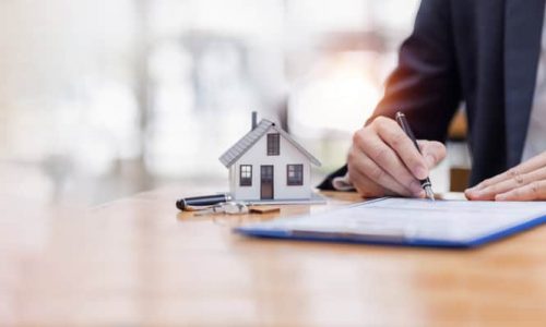 house model with business man signs a purchase contract or mortgage for a buy and sell home insurance concerning mortgage loan Real estate concept, copy space for Editor's text.